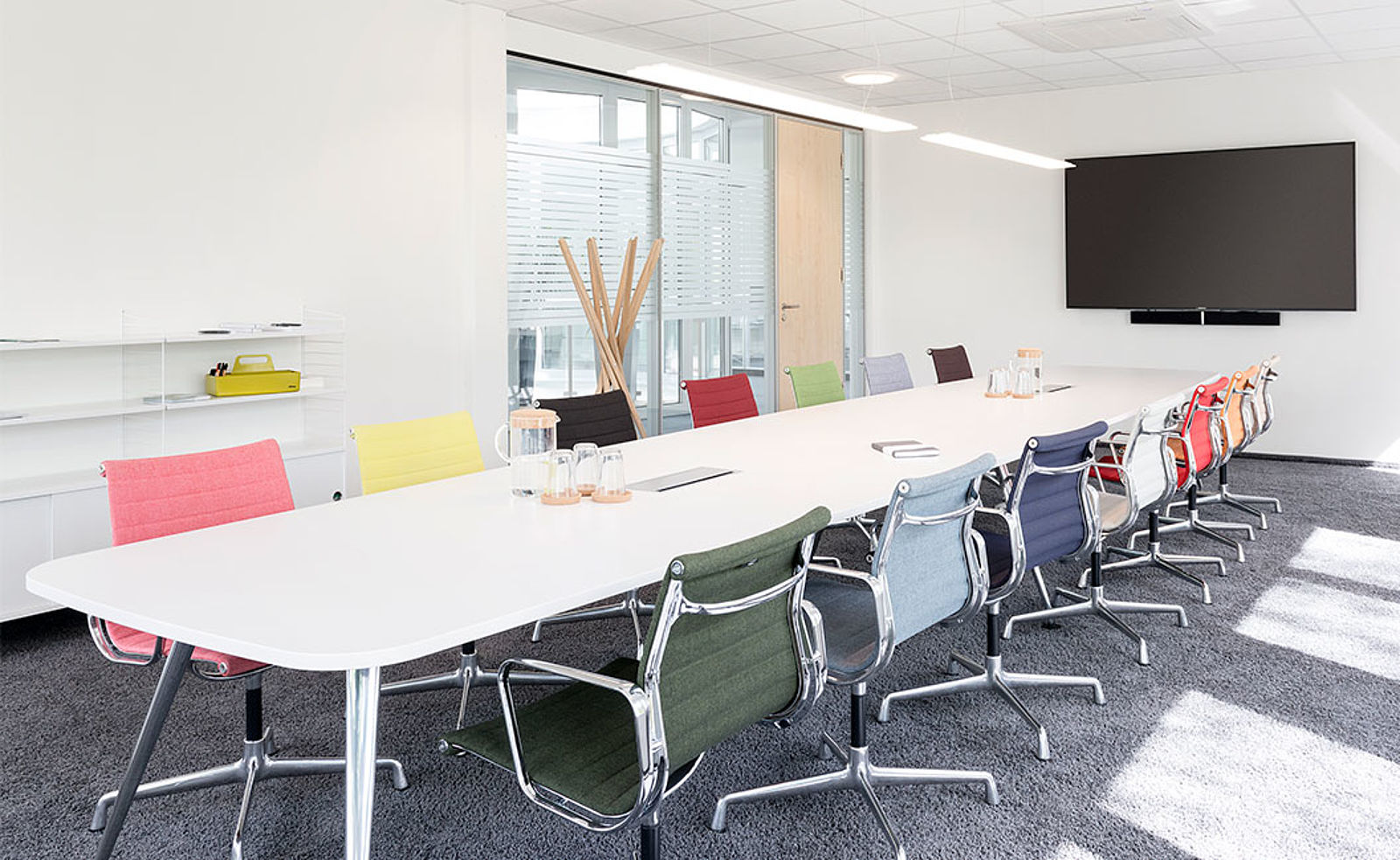 Konferenzraum mit Vitra Konferenztisch und Eames Stühlen in verschiedenen Farben mit POPO Büroplanung